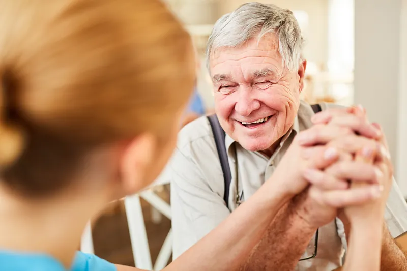 Smiling senior man holding hands with a carer
