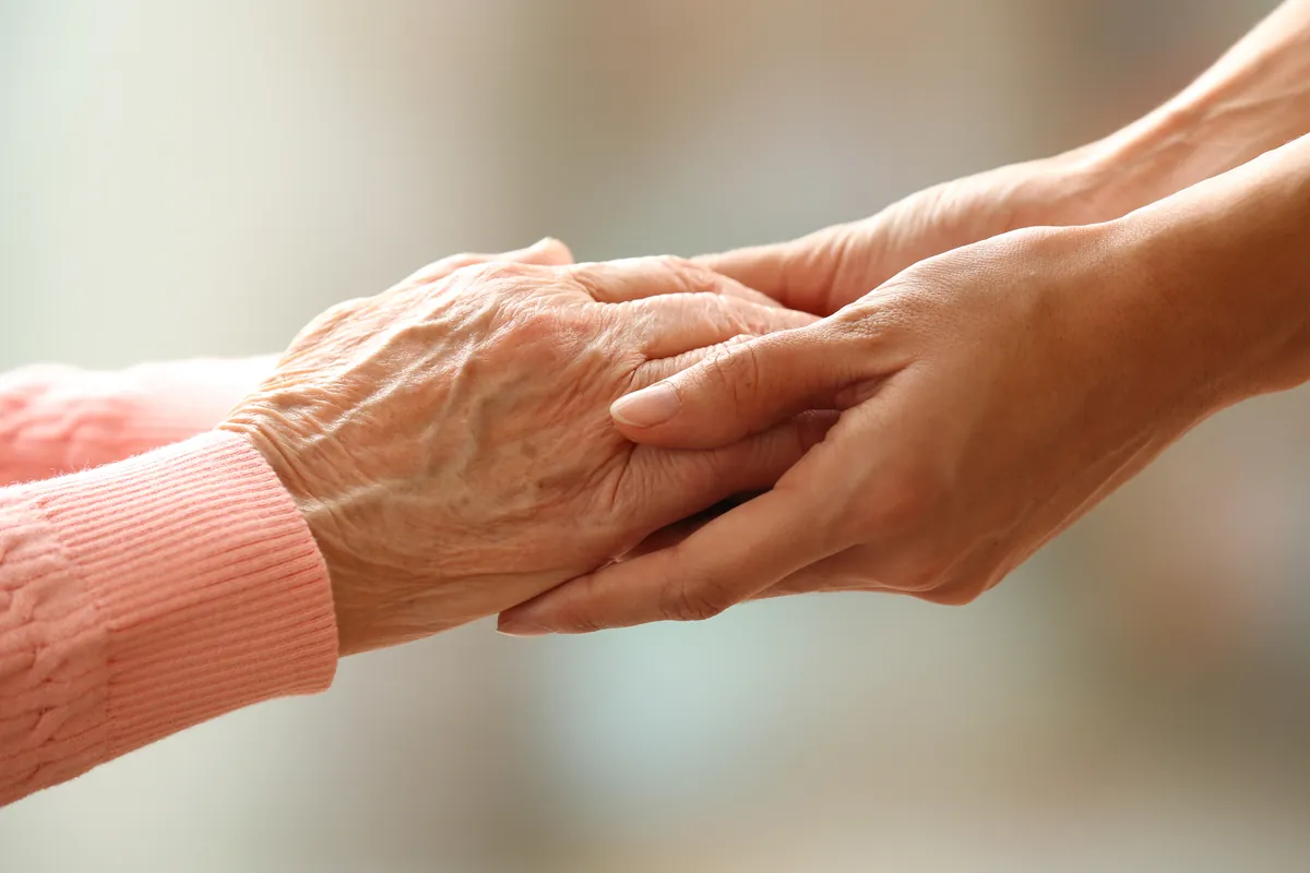Holding hands, one older persons hands, one younger set of hands