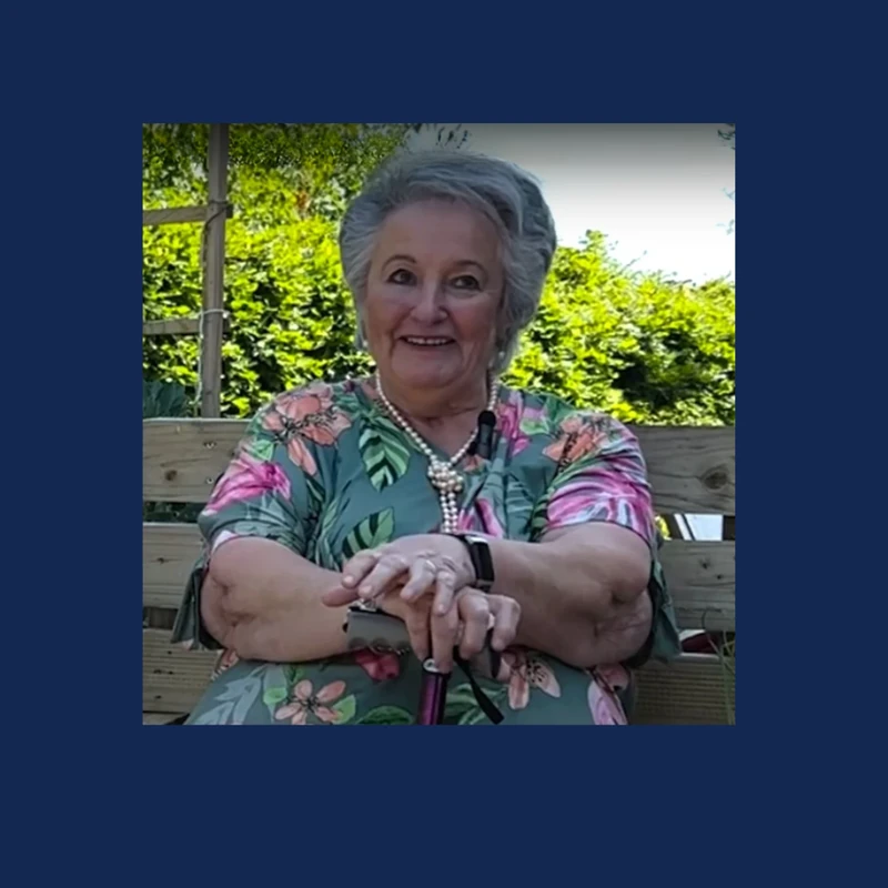 Mary, a Sue Ryder resident, smiling in a garden
