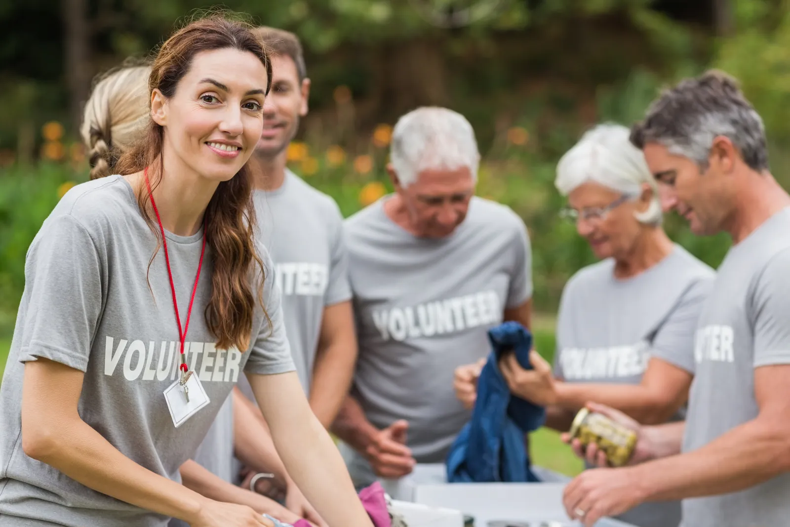 Smiling volunteer in a grey T-shirt with a group of senior volunteers outdoors